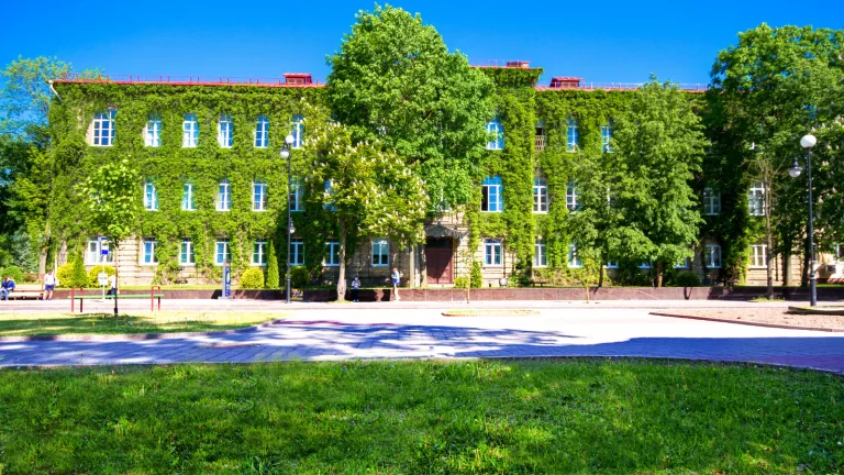蓝天下藤蔓覆盖的格罗德诺国立大学（扬卡·库帕拉）校园建筑、树木与草坪